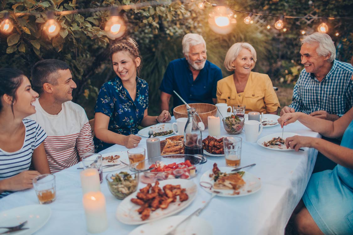 A senior couple wearing Colorado Ear Care hearing aids at an outdoor dinner with their family