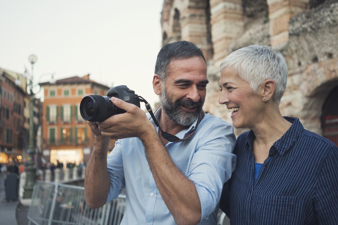 A senior couple wearing Colorado Ear Care hearing aids traveling and taking photos