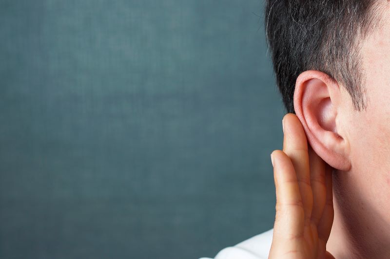 A man hold his hand to his ear because of selective hearing