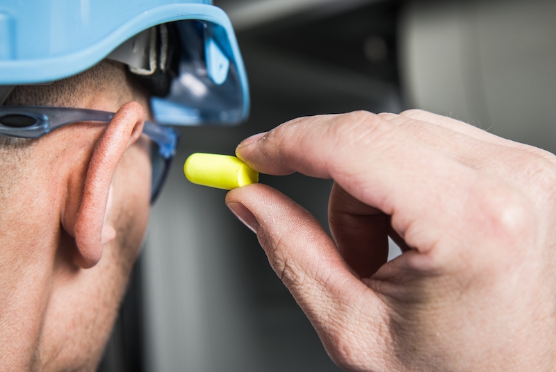 construction worker uses ear plugs to protect his hearing