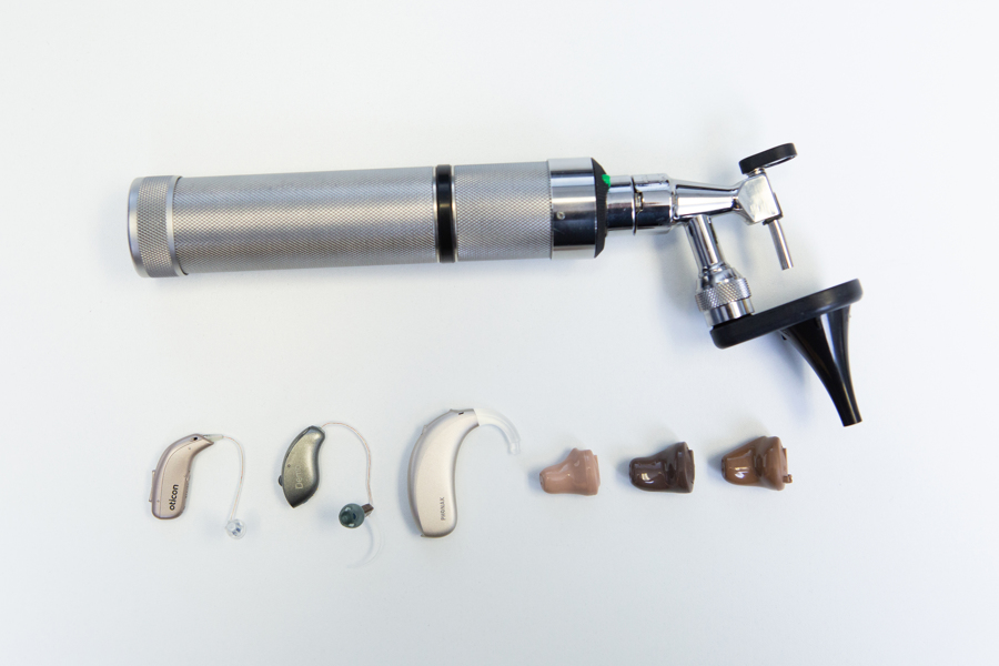 an otoscope next to a lineup of hearing aid styles offered by Colorado Ear Care