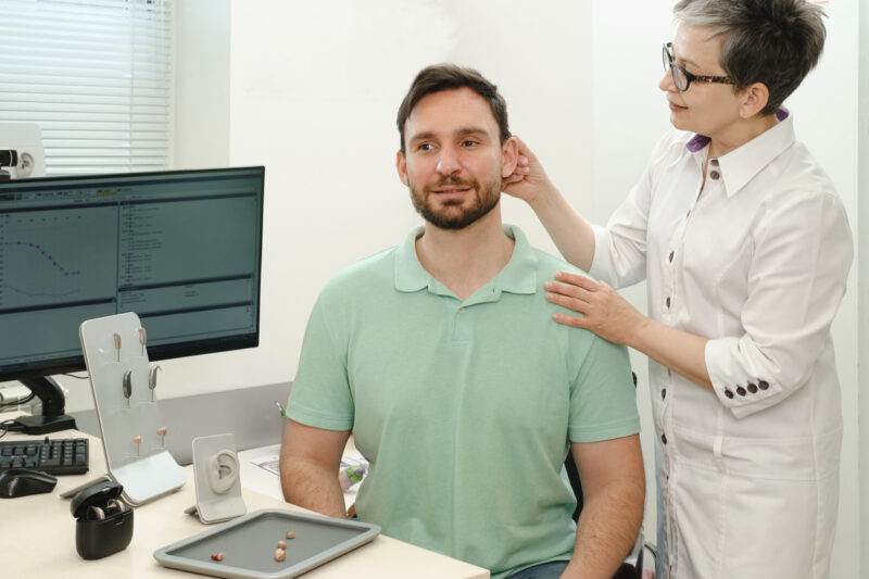 Audiologist fitting a hearing aid on a patient.